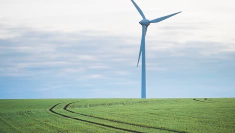 Eine-Langsam-Rotierende-Gigantische-Windturbine-Thront-Auf-Dem-Grünen-Ackerfeld