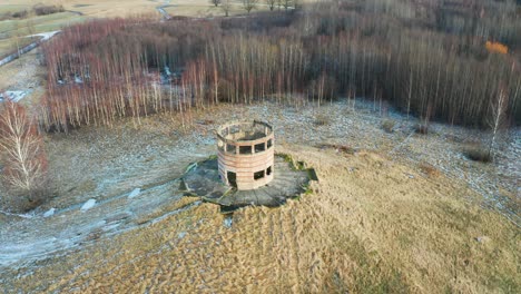 Aerial-view-of-abandoned-military-observation-tower-on-small-hill-near-forest