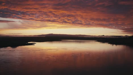 Incredibly-gorgeous-drone-aerial-of-a-red-sunset-or-sunrise-against-a-river