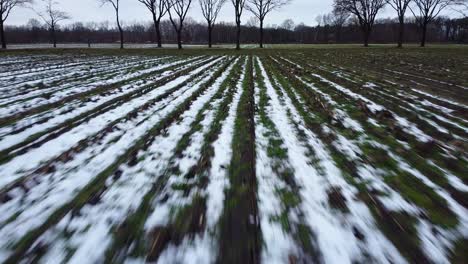 Luftaufnahme-über-Einem-Schneebedeckten-Landwirtschaftlichen-Feld,-Das-Langsam-Schmilzt,-Mit-Der-Autobahn-Im-Hintergrund