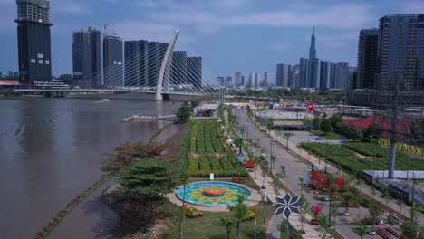 Ho-Chi-Minh-City,-Saigon-River-and-city-skyline-on-sunny,-clear-day-featuring-landmark-building-and-Landscaping-along-River-with-colorful-fountain