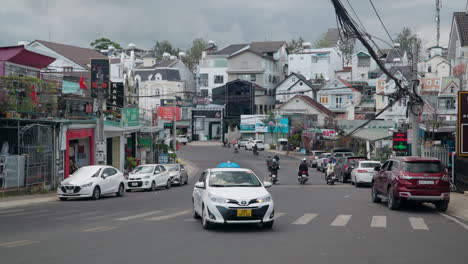 Tráfico-Urbano-De-La-Ciudad-De-Da-Lat-Con-Muchos-Viajeros-En-Motocicletas-Y-Fachadas-De-Edificios-De-Estilo-Francés-En-Días-Nublados