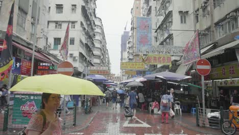 área-De-Mong-Kok-Del-Mercado-Callejero-De-Hong-Kong-Llena-De-Vendedores-Y-Peatones-Con-Sombrillas-Durante-Un-Día-Lluvioso---Cámara-Inclinada-En-Cámara-Lenta