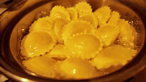 Ravioli-cooks-in-wobbly-pan-of-boiling-water-in-warm-light-close-up