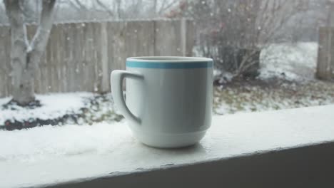 Slow-motion-of-Cup-of-hot-drink-with-a-winter-snow-fall-on-outdoor-background