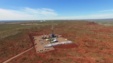 A-drilling-rig-in-a-vast,-barren-landscape-during-the-day,-industrial-equipment-in-operation,-aerial-view