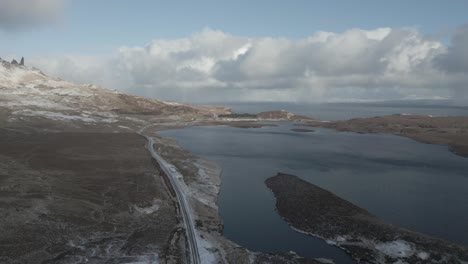 The-skye-bridge-and-loch-alsh-in-the-serene-scottish-highlands,-with-scattered-snow-and-dynamic-clouds,-aerial-view