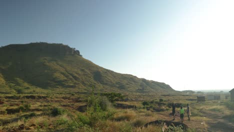 Young-children-from-a-remote-village-walk-along-a-mountain-landscape