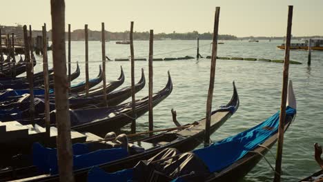 Gondolas,-typical-boats-from-Venice,-moving-on-the-water-in-the-lagoon-near-the-main-square