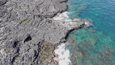 Drone-view-looking-down,-hovering-over-the-rocky-coast-of-Pointe-au-Sel-in-Saint-Leu,-Reunion-Island,-with-a-slow-forward-movement