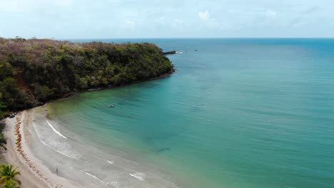 Serene-segresse-beach-in-grenada-with-clear-waters-and-a-single-person-walking,-aerial-view