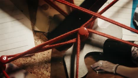 Close-pan-shot-of-the-investigative-board-with-crime-scene-photos-and-red-strings-connecting-the-evidence