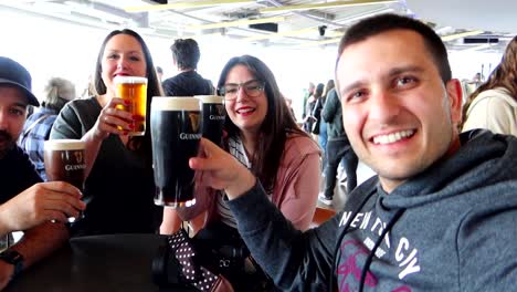 Four-friends-cheers-with-dark-Guinness-beer-in-an-outside-bar-in-Dublin,-Ireland