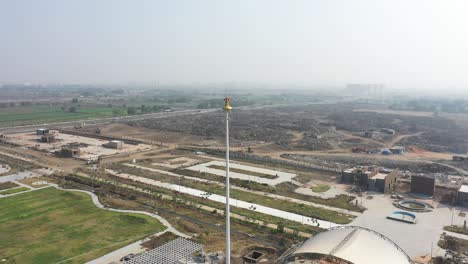 Rajkot-Atal-See-Drohnenansicht-Ashok-Chakra-Dreht-Sich-Um-Die-Morgenkamera,-Im-Hintergrund-Sind-Viele-Große-Gärten-Zu-Sehen,-Rajkot-Neue-Rennstrecke,-Atal-Sarovar