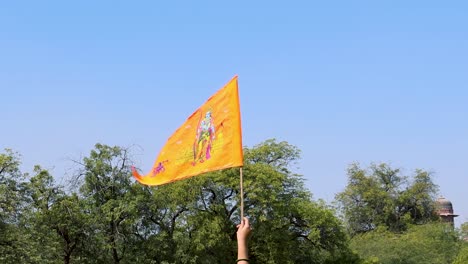 Heilige-Safran-Flagge-Mit-Lord-Rama-Idol-In-Der-Hand-Mit-Strahlend-Blauem-Himmelshintergrund-Am-Tag