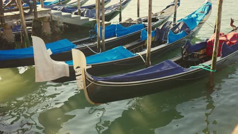 Gondolas,-typical-boats-from-Venice,-moving-on-the-water-in-the-lagoon-near-the-main-square