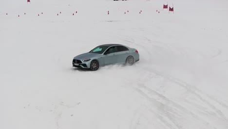 Aerial-view-of-car-on-snowy-race-track-with-traffic-cones-lose-control