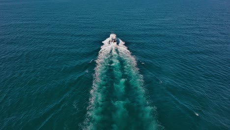 Long-white-wake-trail-of-speedboat-cruising-over-calm-blue-sea-water