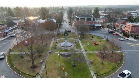 Rising-drone-shot-of-circular-park-surrounded-by-roundabout-with-driving-cars