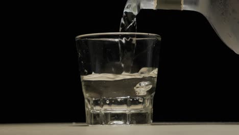 Pouring-pure-transparent-alcohol-on-shot-glass-in-studio