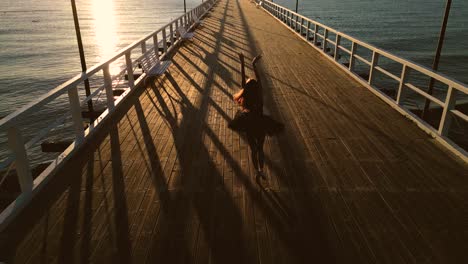 Bailarina-Expresando-Pasos-De-Ballet-En-El-Muelle-De-La-Playa-Al-Atardecer