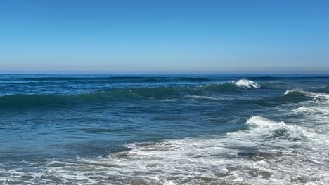 Olas-Del-Océano-Rompiendo-Y-Rociando-Juntas-Durante-La-Marea-Real-Sobre-El-Océano-Azul-Y-El-Cielo-Azul