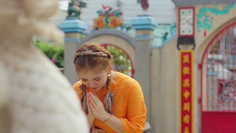 Close-up-of-an-Asian-girl-in-national-costume-praying-at-a-pagoda