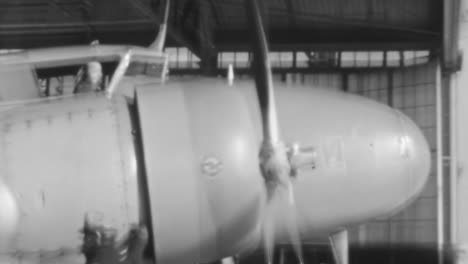 Engine-Mechanic-Standing-Beside-a-Rotating-Propeller-Aircraft-in-Hangar-in-1930s