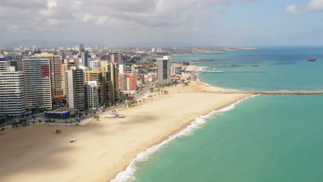 Aerial-view-of-the-buldings-in-front-of-the-sea,-the-empty-beach-in-a-cloudy-day,-Fortaleza,-Ceara,-Brazil