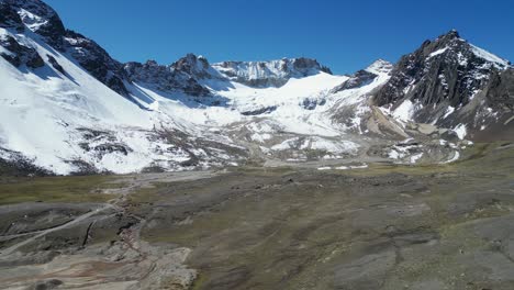 Clear-mountain-air-in-high-altiplano,-aerial-rises-before-snowy-peak