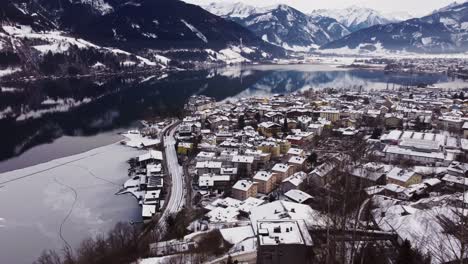 Aerial-view-Zell-am-see,-winter-wonderland-village,-train-arrive,-dolly-in,-day