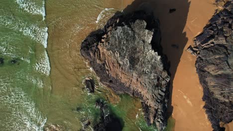 Luftaufnahme-Der-Felsformationen-Bedruthan-Steps-Mit-Meereswellen,-Die-über-Goldenen-Sand-Rollen,-Cornwall