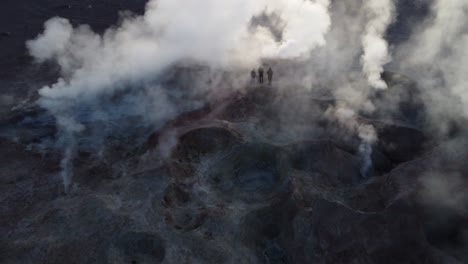 Aerial:-Tourists-stand-backlit-amid-steaming-geysers-at-Sol-de-Manana
