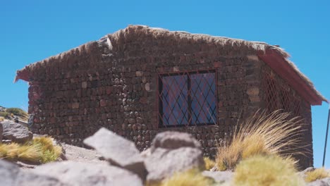 Casa-De-Piedra-En-El-Desierto-Junto-Al-Lago-Rodeado-De-Montañas-Día-De-Cerca