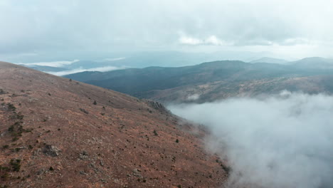 Neblige-Berglandschaft-Mit-Wolken,-Die-Im-Morgengrauen-über-Die-Hügel-Rollen,-Weitwinkelaufnahme