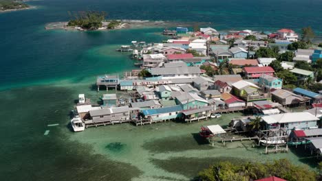 Aerial-Drone-Landscape-of-Caribbean-Coastline-Houses,-Utila-Honduras-Bay-Island-with-Pristine-Turquoise-Water