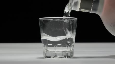 Transparentes-Getränk-In-Ein-Glas-Gießen,-Weißer-Hintergrund,-Nahaufnahme