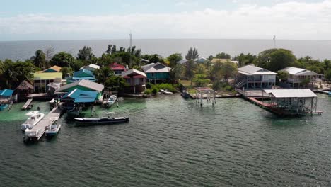 Aerial-Drone-Landscape-of-Island-Houses-Docks-Caribbean-Sea-in-Utila-Honduras,-Blue-Skyline-in-Sunny-Daylight,-Bay-Hotels