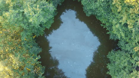 Toma-Aérea-Ascendente-Revela-Una-Pequeña-Reserva-De-Agua-Donde-Se-Extrae-Agua-Para-Riego-De-Precisión-De-Una-Exuberante-Plantación-De-Trigo-Que-Muestra-Prácticas-Agrícolas-Sostenibles-En-Alemania-Bravaria