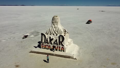 Aerial-circles-Dakar-Monument-made-of-salt-on-Uyuni-Salt-Lake,-Bolivia
