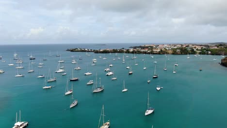 Yachts-anchored-in-prickly-bay-marina,-grenada,-with-coastal-buildings,-aerial-view