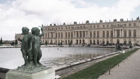 Backyard-and-view-on-the-back-of-the-baroque-mainbuilding-of-the-famous-castle-Versailles-in-Paris-France-with-statues,-pool-and-tourists-in-spring-time