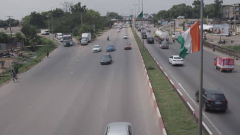 Ivorian-Flag-Waving-On-A-Pole-In-Middle-Of-A-Highway-With-Incoming-Traffic