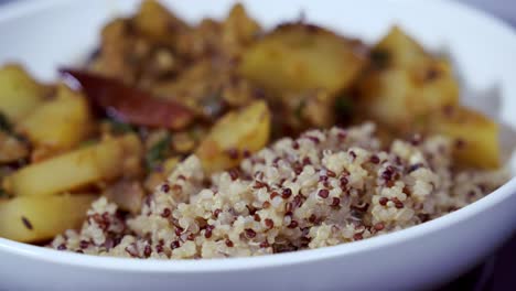 Nahaufnahme-Eines-Rotierenden-Papaya-Currys-In-Einer-Weißen-Schüssel-Mit-Quinoa-An-Der-Seite