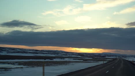 Viaje-Por-Carretera-Al-Atardecer-A-Través-Del-Paisaje-Nevado-De-Islandia-Desde-La-Perspectiva-Del-Conductor,-Nubes-Pintando-El-Cielo