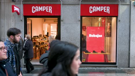 People-walk-past-the-Spanish-multinational-manufacturing-and-footwear-retail-brand-Camper-store-in-Madrid,-Spain