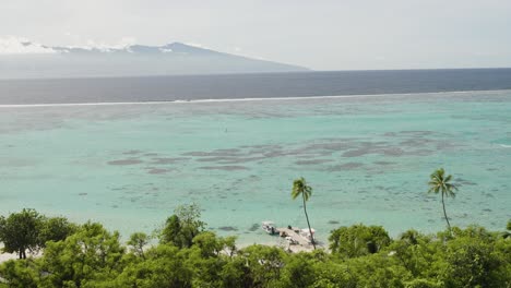 Cinematic-shot-of-private-resort-boat-jetty-on-Moorea-island-with-Tahiti-in-the-background