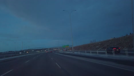 Vista-Del-Coche-De-Carretera-Pasando-Bajo-El-Puente-Por-La-Noche-En-Calgary,-Alberta,-Canadá