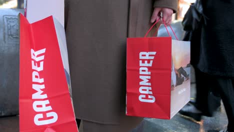 A-customer-holds-shopping-bags-from-the-Spanish-multinational-manufacturing-and-footwear-retail-brand-Camper-store-in-Madrid,-Spain