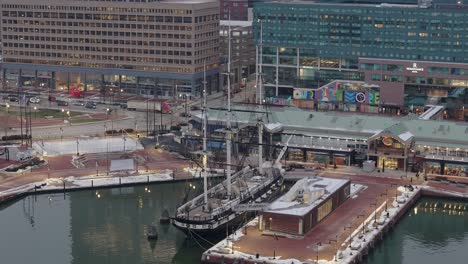 Circling-Aerial-of-Boat-in-Baltimore-Harbor-in-Daytime,-Cars-in-Background